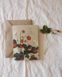 a greeting card with strawberries and daisies on it next to a leafy plant