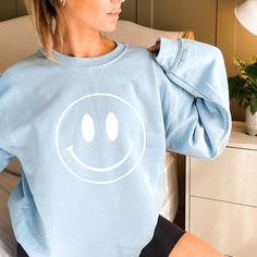 Looking for the perfect gift for your girlfriend or friend? Look no further than the smiley face shirt! This fun and cheerful shirt is sure to put a smile on her face, whether she's wearing it for everyday wear or as a festive gift. Plus, it's made from high-quality materials so it will last long. So why not buy her this adorable shirt today?  COLORS  Black  Light Blue Natural / Sand Pink White  SIZE CHART  See photos for size chart PRODUCT DETAILS 🌺 50% cotton, 50% polyester 🌺 Medium-heavy fabric (8.0 oz/yd² (271.25 g/m²) 🌺 Loose fit 🌺 Sewn-in label 🌺 Runs true to size CARE INSTRUCTIONS 🌺Machine wash cold, inside-out, gentle cycle with mild detergent and similar colors. Use non-chlorine bleach, only when necessary. No fabric softeners. 🌺Tumble dry low, or hang-dry for longest life. Trendy Smiley Face Loungewear Tops, Cute Long Sleeve Smiley Face Top, Trendy Smiley Face Tops For Loungewear, Smiley Face Top For Loungewear, Relaxed Fit Smiley Face Top For Loungewear, Trendy Long Sleeve Tops With Smiley Face, Fun Smiley Face Crew Neck Top, Smiley Face Crew Neck Tops For Loungewear, Fun Crew Neck Top With Smiley Face