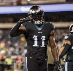 a philadelphia eagles football player holding his helmet and walking off the field during a game