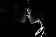 black and white photograph of a man kissing a woman's face in the dark