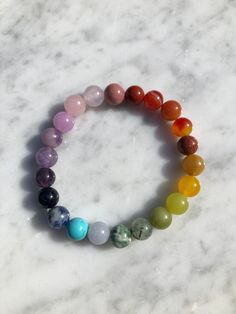 Introducing our exquisite handmade Chakra Gemstone bracelet. This stunning design features a combination of Red Jasper, Orange Carnelian, Red and Yellow Aventurine, Lemon Jade, Peridot, Green Moss Agate, Green and Blue Spot Jasper, Purple Dyed Chalcedony, Kunzite, Blue Magnesite, Goldstone, and Rhodonite. Each stone in this design is a a celebration of the vibrant colors found in nature and each holds its own unique hue, representing different aspects of the natural world. Beads are 8mm each, on a stretch cord which is double strung for durability. Each bracelet is carefully placed on a selenite plate overnight to cleanse and recharge its energy, ensuring it has the highest vibrational quality.  From the grounding red of Red Jasper to the soothing blue of Blue Magnesite, these colors reson Natural Stones Crystals For Meditation, Holistic Crystal Bracelet With Round Gemstone Beads, Holistic Bracelets With Natural Stones, Agate Stretch Bracelet With 8mm Beads For Healing, Spiritual Bracelets With Natural Stones, Handmade Crystal Bracelet With Round Beads For Meditation, Handmade Holistic Crystal Bracelet With Round Beads, Meditation Bracelets With Round Gemstones, Gift Natural Stone Beaded Bracelets With Round Beads