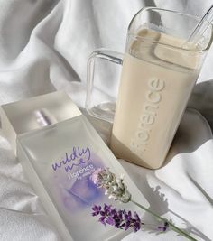 a bottle of milk next to a glass with a flower in it on a white blanket