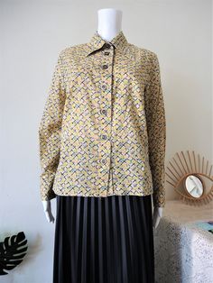 Beautiful True Vintage blouse from the 1970s. Slightly fitted cut, very light fine cotton fabric with flowers on grid print. Large pointed Seventies collar, button down, buttoned cuffs. Looks great tucked into a pair of highwaist flared jeans and combined with clogs! BRAND: No brand label anymore ERA: 1970s COLOR: Sand, yellow, pink, green, black, blue FABRIC: 100% cotton SIZE: No size tag, fits best size M to small L (or S for a more relaxed fit) - please check measurements below for reference Spring Patterned Shirt With Retro Print, Spring Retro Print Patterned Shirt, Patterned Retro Print Shirt For Spring, Retro Patterned Shirt For Spring, Spring Cotton Blouse With Lapel Collar, Cotton Blouse With Lapel Collar For Spring, Retro Spring Button-up Shirt, Patterned Button-up Cotton Blouse, Patterned Cotton Button-up Blouse