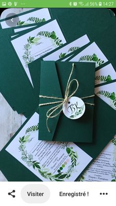 some green envelopes tied with twine on top of each other and decorated with greenery