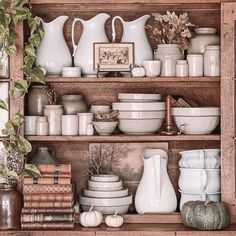 a shelf filled with dishes and vases on top of wooden shelves next to books