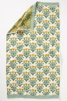 a green and yellow floral print blanket on a white background with a gold foiled edge