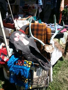 an assortment of clothes and scarves are piled on top of a cart in the grass