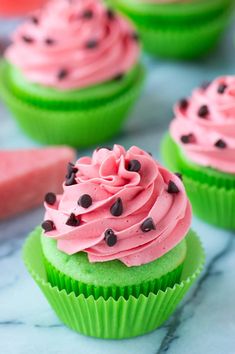 some cupcakes with pink frosting and chocolate chips on top are sitting on a marble surface