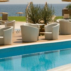 an empty pool with chairs and umbrellas next to the water in front of it