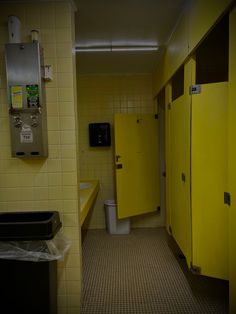 a bathroom with yellow walls and tile flooring next to a trash can on the wall