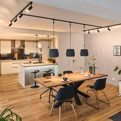 a dining room table with chairs and a fire place in the center is surrounded by potted plants