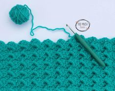 the crochet stitch is being worked on by a ball of yarn and a knitting needle