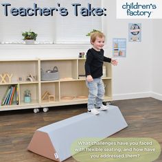 a young boy standing on top of a blue block in front of a book shelf