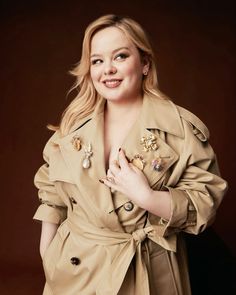 a woman in a trench coat posing for a photo with her hands on her chest