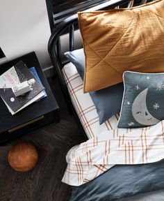 a bed topped with lots of pillows next to a night stand and table filled with books