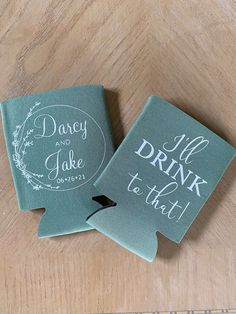 two green coasters with white lettering on them sitting on a wooden table next to each other