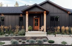 a house with black siding and wood trimmings on the front door, steps leading up to it