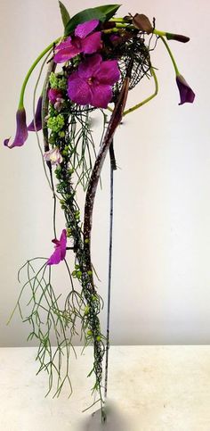 purple flowers and greenery in a vase on a table