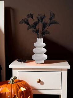 a white vase filled with flowers sitting on top of a table next to a pumpkin