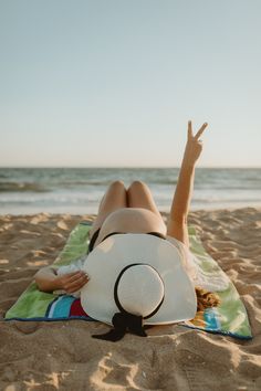 a woman laying on top of a towel on the beach