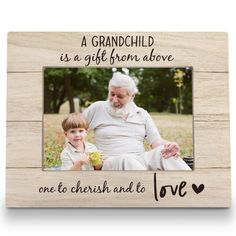 an old man and young boy are sitting in front of a wooden frame that says, a grandchild is a gift from above one to cherish and love