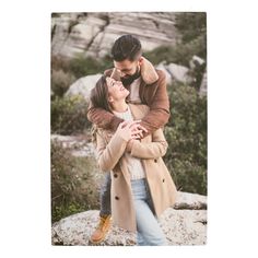 a man and woman embracing each other in front of some rocks