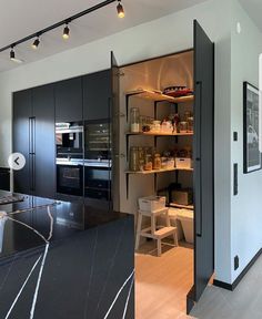 an open kitchen with black cabinets and marble counter tops, along with stainless steel appliances