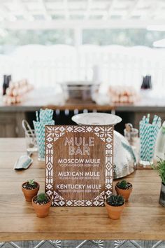 a wooden sign sitting on top of a table next to potted plants and other decorations