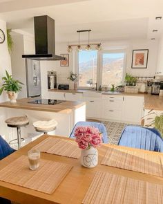 a kitchen table with blue chairs and a vase filled with flowers sitting on top of it