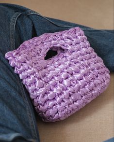 a purple purse sitting on top of a pair of jeans