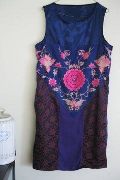 FREE SHIPPING FOR ALL US AND CANADIAN CUSTOMERS! This silk babydoll dress is designed with dark blue silk, espresso lace and a piece of vintage Miao embroidery. The Miao ethnic group in Southwest China makes exquisite embroideries. Compared to Han embroideries, Miao embroideries are wild and romantic, not afraid to use bold colors and cool contrasts. The beautiful embroidery you see features a typical pattern of a flower surrounded by a butterfly and two birds. In Miao folklore, butterfly is vie Fitted Patchwork Wedding Dress, Sleeveless Silk Dress With Lace Patchwork, Embroidered Purple Silk Dress, Traditional Sleeveless Silk Dress, Sleeveless Embroidered Silk Dress, Purple Silk Dresses With Floral Embroidery, Fitted Patchwork Dresses For Festive Occasions, Traditional Blue Sleeveless Dress, Miao Embroidery