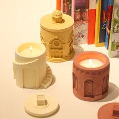 three candles sitting on top of a table next to books and other items in front of them