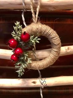 a christmas wreath hanging from a rope with berries and greenery on it's end