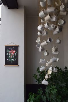 coffee cups are hanging from the ceiling in front of a sign