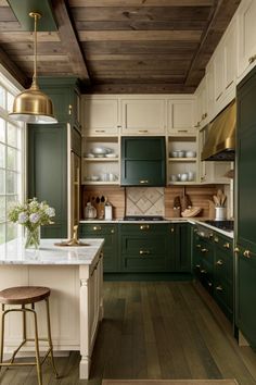 a kitchen with green cabinets and white counter tops, gold accents and stools in front of the island