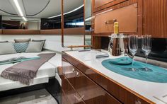 the interior of a boat with wooden cabinets and white counter tops, two wine glasses on a tray