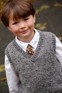 a young boy wearing a sweater vest and tie