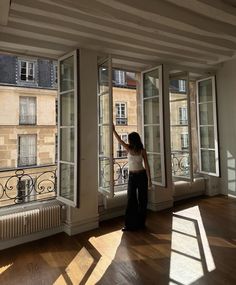 a woman standing in an empty room looking out the window