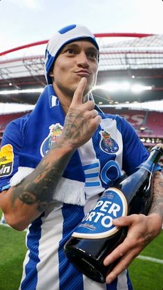 a man in a blue and white striped shirt holding a bottle of beer at a stadium