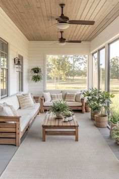 a porch with couches, tables and potted plants on the front porch area