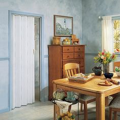 a dining room table with chairs and a dresser in the corner next to an open door