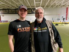 two men standing next to each other in a baseball field wearing black shirts and hats