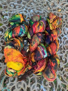 a bunch of balls of yarn sitting on top of a piece of metal mesh covered in multicolored dye