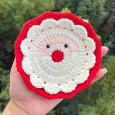 someone is holding up a crocheted christmas ornament in front of some trees