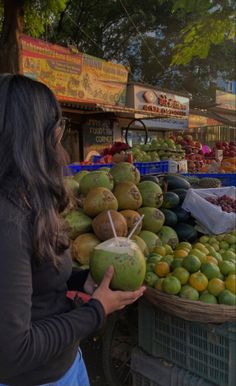 a woman standing in front of a fruit stand