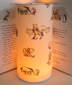 a lit candle with winnie the pooh images on it and an open book beside it