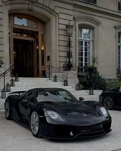 a black sports car parked in front of a large building with steps leading up to it