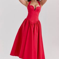 a woman in a red dress posing for the camera with her hands on her head