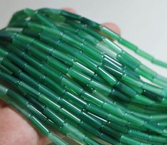 a hand holding a bunch of green glass beads