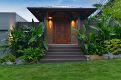 a house that has some plants in the front yard and stairs leading up to it